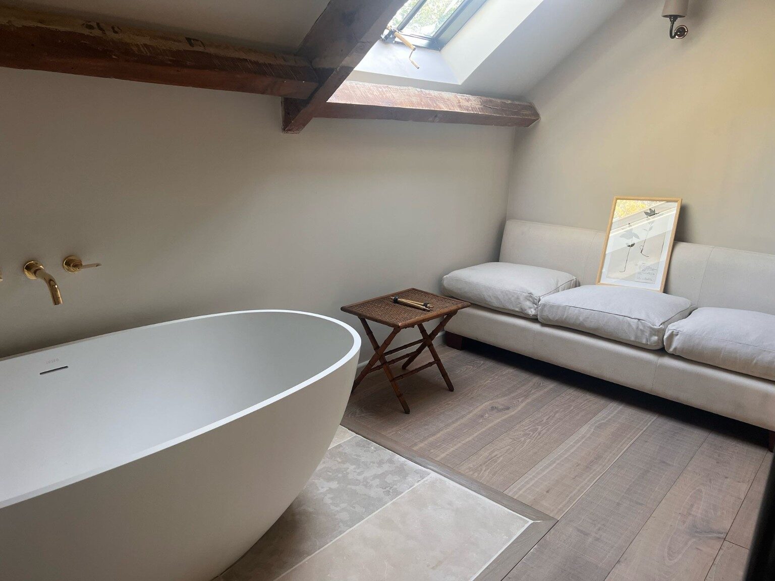 Completed bathroom renovation with freestanding bath, exposed beams and timber flooring