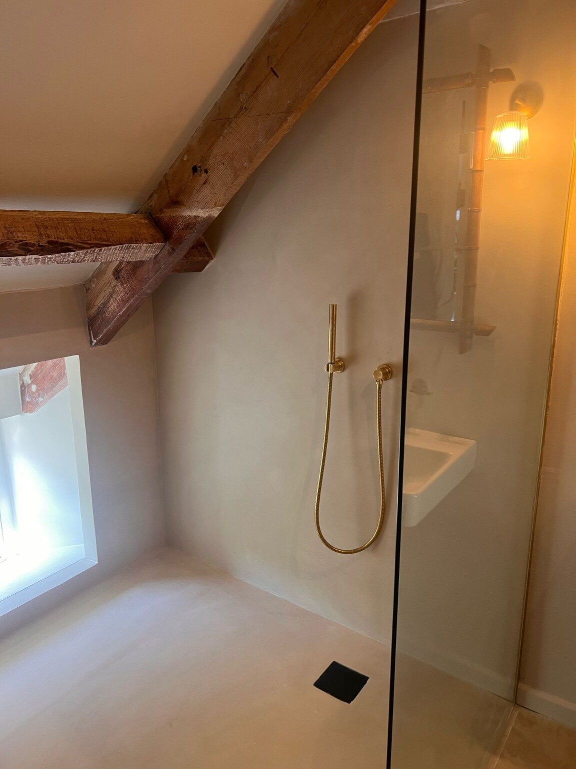 Walk-in shower with exposed timber beam and brass fittings
